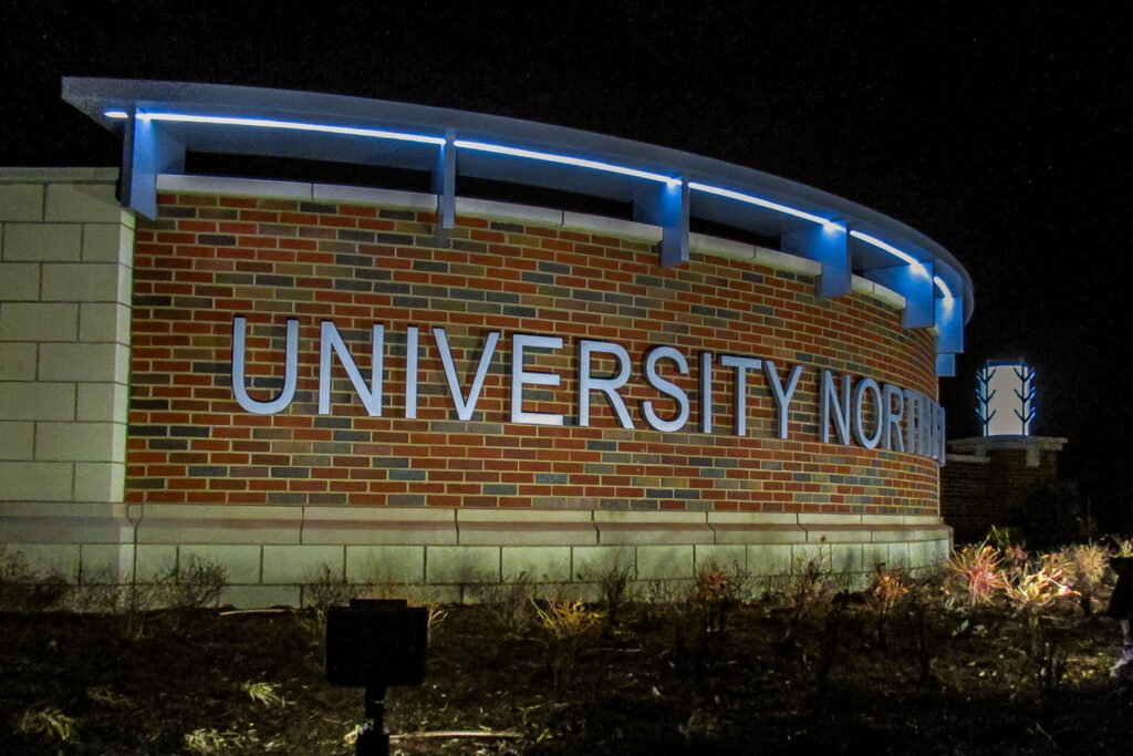 Exterior sign featuring LED flat-cut cast letters, cast stone, masonry, and brickwork for University North Park shopping center.