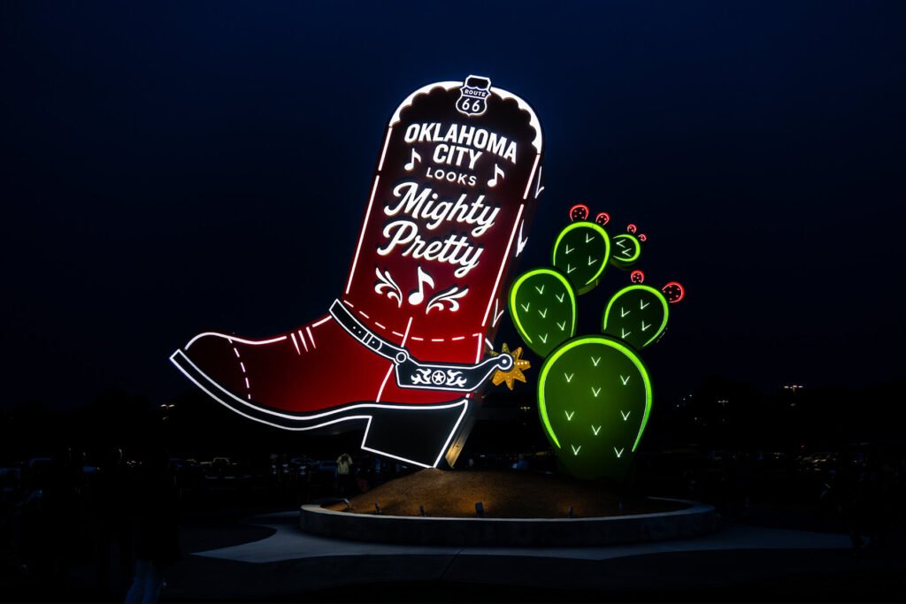 Exterior night view of illuminated push-through channel sign featuring a boot and cactus sculpture for Kicks 66 in Oklahoma City, Oklahoma.